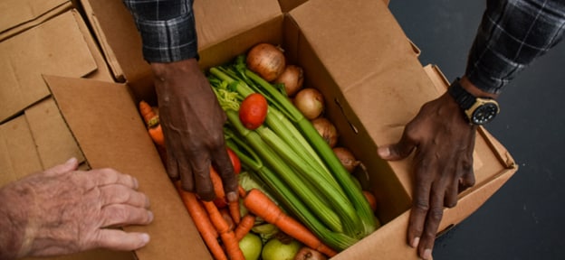 Hands picking out vegetables from a box