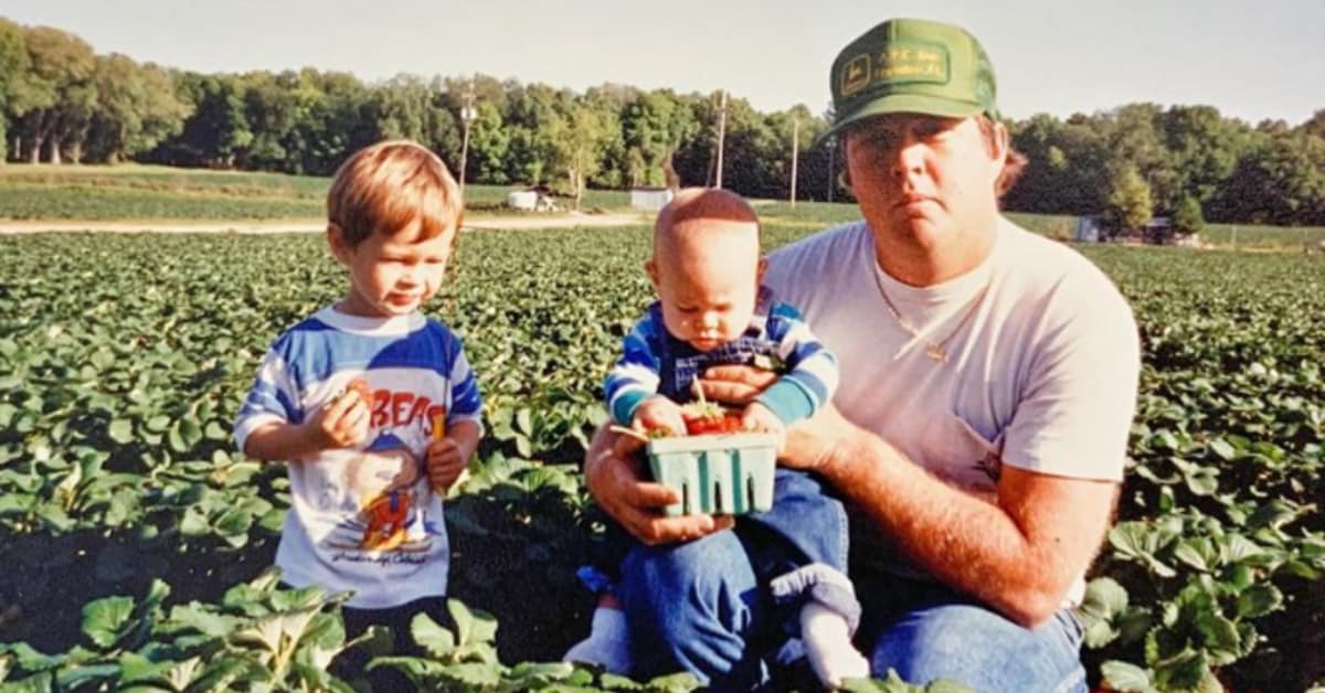 A person holding a baby and a basket of strawberries